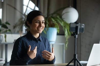 smiling indian young woman coach or speaker record live video broadcast on modern smartphone gadget, positive ethnic millennial girl shoot webinar or online training course on cellphone device