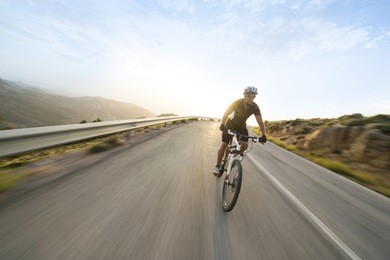 cyclist man riding mountain bike in sunny day on a mountain road. image with flare.