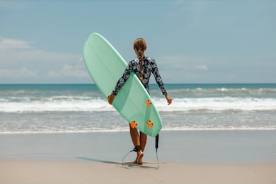 woman surfer with surfboard going to surf at seaside. girl holding surfboard o and goes to the ocean sea, a view from the back