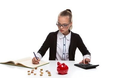 money saving concepts. teenager blond girl posing with coins and moneybox. calculating income with calculator for savings.horizontal image