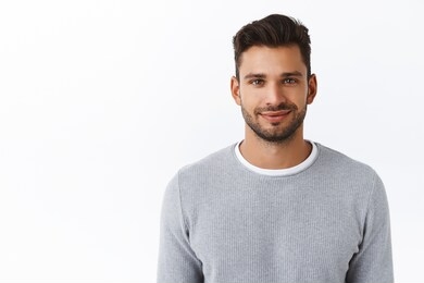 close-up happy smiling confident macho man with bristle in stylish grey sweater, looking trustworthy and sincere with friendly kind grin, standing white background self-assured and motivated