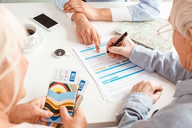 african descent woman travel agent at office pointing at document for senior couple fulfill insurance form close-up