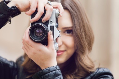 portrait of a pretty young tourist taking photographs with vintage retro camera
