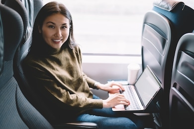 portrait of cheerful asian female enjoying transportation via train with laptop computer learn course remotely, attractive woman blogger working online during journey using laptop computer in wagon