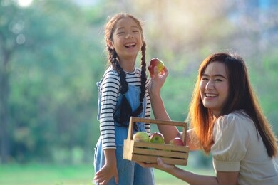 happy asian mother and daughter moments with love in summer park, laughing at the camera
