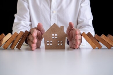 home insurance concept. small  house covered by hands insurance concept residential house