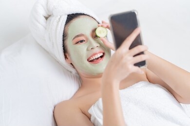 asian woman is facial mask at home. she is live for her friends.