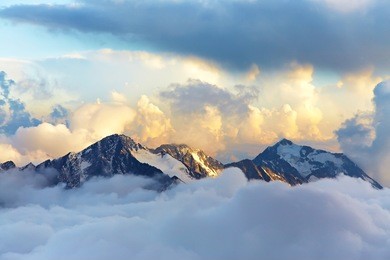 alpine landscape with peaks covered by snow and clouds