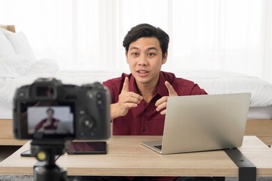 excited funny young attractive asian influence man vlogger talking on live streaming, broadcast with internet subscribers. social media people, content maker, e-commerce concept. working at home.