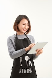 successful hypermarket employee with black apron holding modern tablet isolated on white background with copyspace