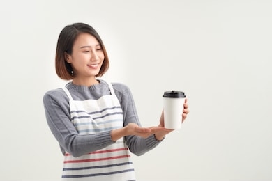 coffee cup to go being held out by a barista, waiter, or professional