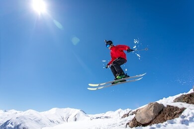 
a skier jumps over a mountain skiing in the background of the sun