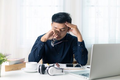 asian male businessman with stressful headaches from working on his desk.
