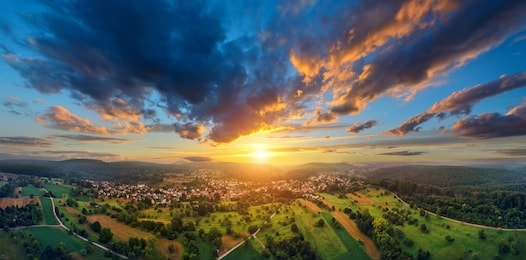 aerial panorama of a vast landscape with a small town at a gorgeous colorful sunset with dramatic sky