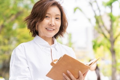 asian senior age woman who fills out a schedule book,outdoor