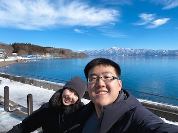 romantic asian couple looking at camera while standing outdoors.
make selfie photo on travel.
happy and loves emotions concept.