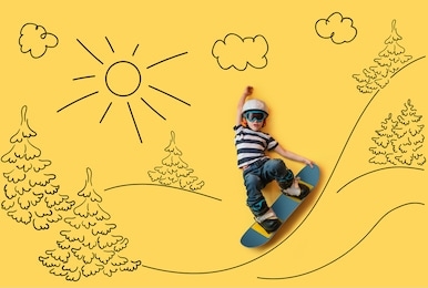 the little boy dreaming about winter season and snowboarding. childhood and dream concept. conceptual image with boy who conquers big mountains on a snowboard. yellow background. dream about sports.