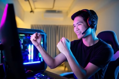 young asian handsome pro gamer feel excited while playing in online cyber sport game at home