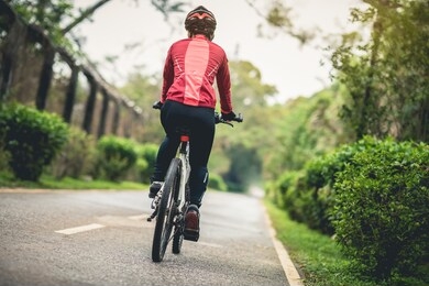 woman cyclist riding a bike on sunny park trail in spring