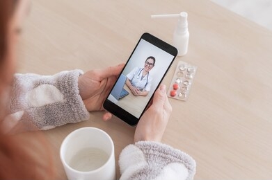 unrecognizable woman on online consultation with a doctor on a cell phone. the girl is sick and talks to the attending physician on a video call from home. close-up of the screen.