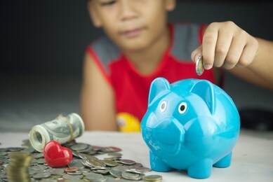 boy drop money coins to piggy bank. concept of insurance money savings for retirement planning .