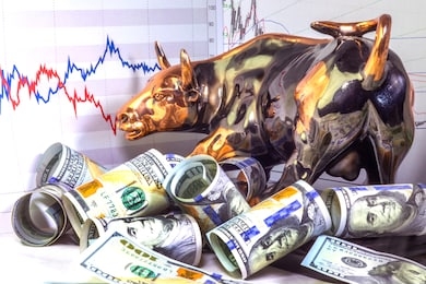 concept of financial investment in bull market.  copper bull near rolled one hundred us dollar bills. stock market prices chart in background.