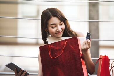 beautiful smile young asian woman hold smart phone purchase and pay online with credit card. shopping on holiday sale season concept. city girl lifestyle happy outdoor activity.