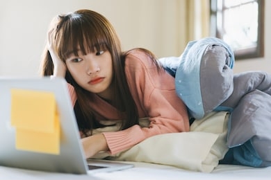 asian teenager woman in bedroom and use computer for work and study in morning on weekend. using internet for social distance and stay at home concept.