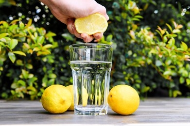 squeezing a lemon into the water. cooking lemon water.