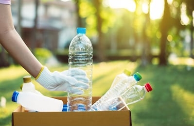 volunteer woman holding plastic bottle into paper box at public park,dispose recycle and waste management concept,good conscious mind,environmentally friendly