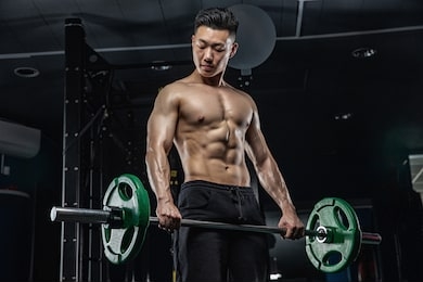 asian handsome man posting with dumbbells in dark gym