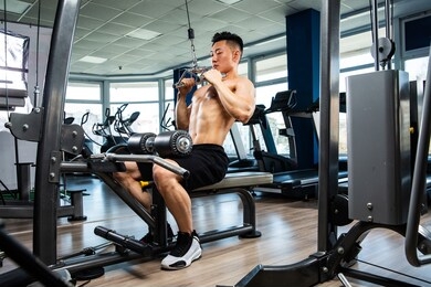 asian handsome man posting with dumbbells in dark gym