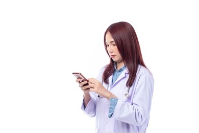 beautiful portrait friendly asian female doctor or nurse with mobile phone in hands and text messaging at medical clinic isolated on white background.