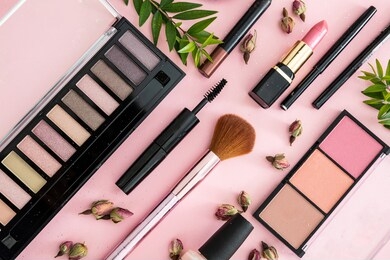 make up natural cosmetics flat lay. lipstick and nail polish, eye shadows and blush, brushes, pencils and rose buds against pink color background.