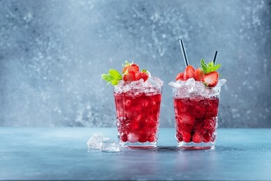 red cocktail with ice and mint. bar concept. strawberry mojito with mint and ice on the blue background, selective focus image