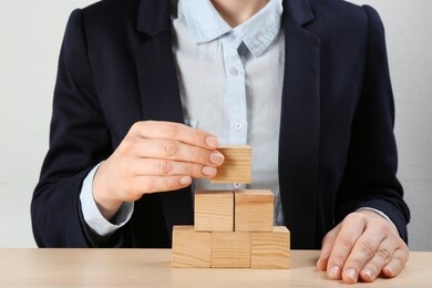 woman building pyramid at wooden table, closeup. career promotion concept