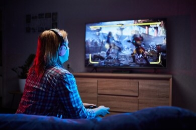 portrait of crazy playful gamer , girl enjoying playing video games indoors sitting on the sofa, holding console gamepad in hands. resting at home, have a great weekend