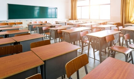 empty classroom with desks, chairs and chalkboard.