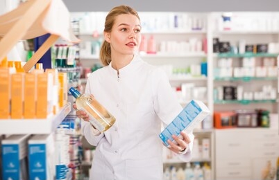 glad female pharmacist offering help in choosing at counter in pharmacy