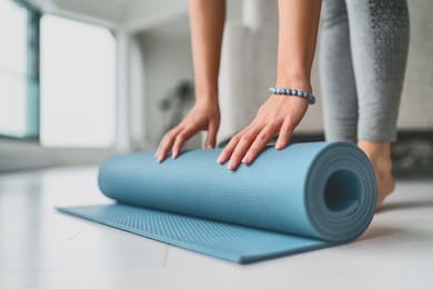 yoga at home woman rolling exercise mat in living room of house or apartment condo for morning wellness yoga practice.
