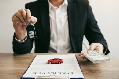car salespeople are holding car keys by submitting to new car buyers with car insurance concept.