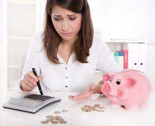 woman is counting her money - sitting sad at desk and has lost her dreams