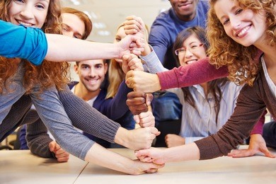 students stacking fists for cooperation and teamwork in a university