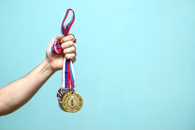 the male hand of the winning athlete holds the highest-ranking medals on a blue background space for text