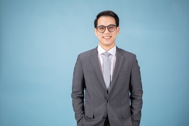 smiling asian man in pants and shirt standing near blank wall. concept of businessman. mock up