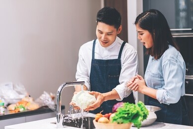 young adult asian couple cooking together and washing vegetables and fruits in the kitchen - housework and lifestyle concept