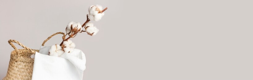 straw wicker basket, natural cotton fabric, cotton flower branch on gray background. bamboo basket stylish interior item eco design handmade. decor of home. natural eco materials, storage basket