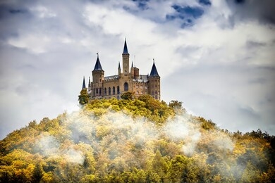 castle on a wooded mountain in the fog under clouds, hohenzollern, germany