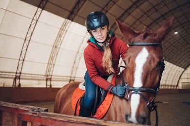 pretty young woman riding a horse in the arena for equestrian sport