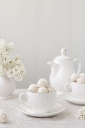 raffaello candies with whole almonds, coconut powder in cups on a white background.